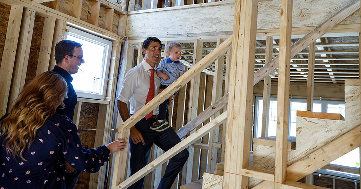 Justin Trudeau visting a housing development under construction in Vancouver. He his holding a child with his left arm