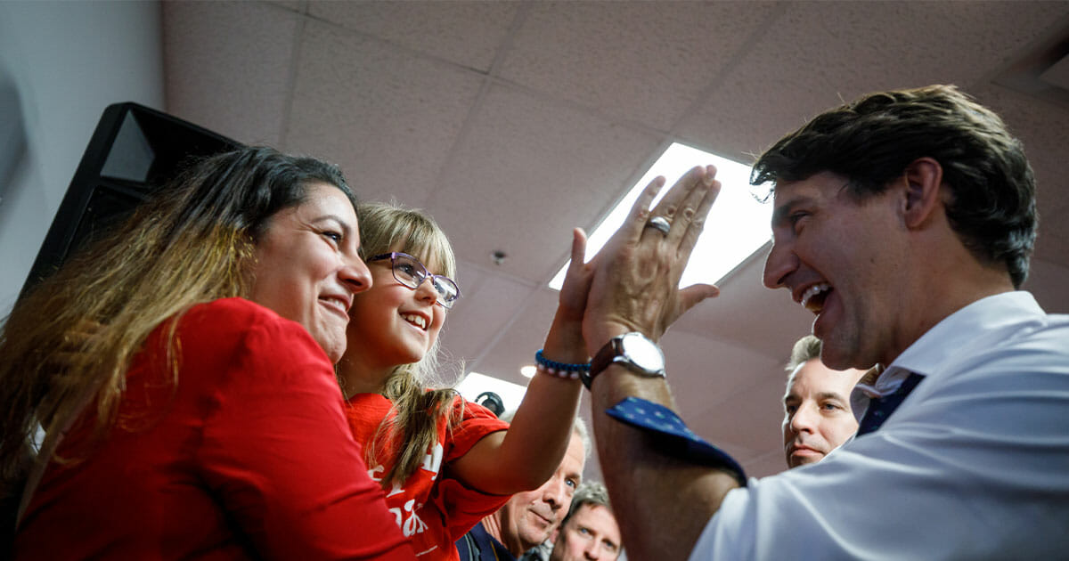 Justin Trudeau smiling and giving a high-five to a kid